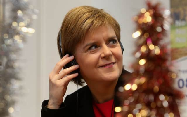 First Minister Nicola Sturgeon listens to a call to an elderly person made by a Christmas volunteer at Silver Line Scotland. Picture: PA