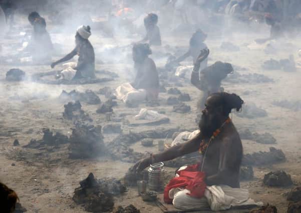 Hindu holy men perform a ritual by burning dried cow dung cakes in earthen pots. Picture: AP