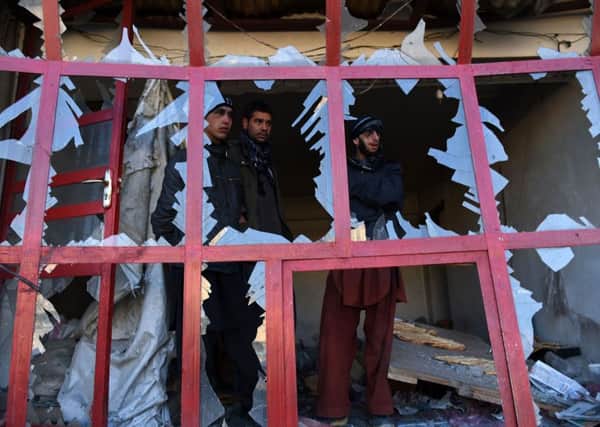 Afghan onlookers watch through the broken windows of a bakery at the site of a suicide car bomb in Kabul. Picture: AFP/Getty Images