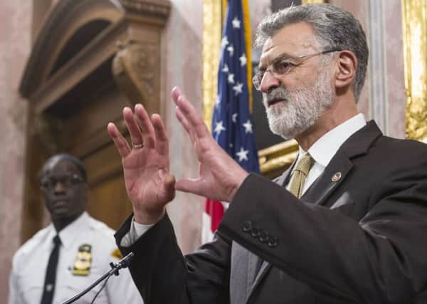Cleveland Mayor Frank Jackson appeals for calm; a protester with a picture of Tamir Rice. Picture: AP