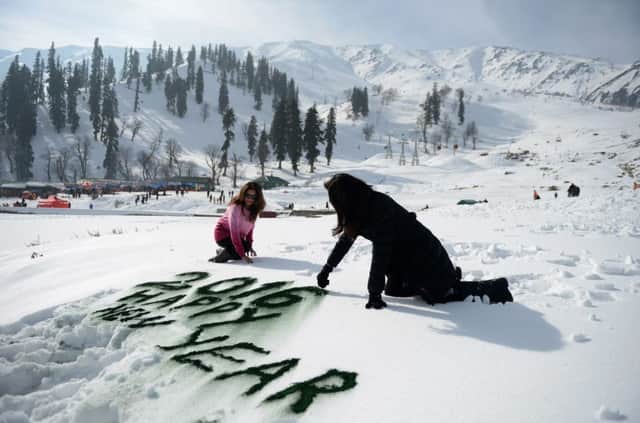 Indian tourists write in the snow as they celebrate the New Year in Gulmarg. Picture: AFP/Getty Images