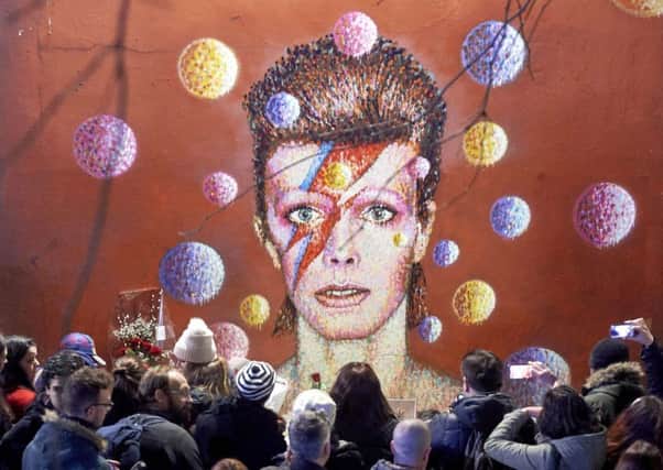 Fans gather to pay tribute to Bowie at a mural in his birthplace Brixton yesterday. Picture: AFP/Getty Images