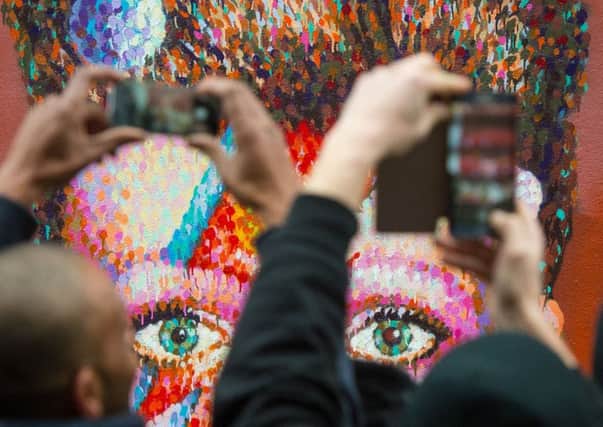 People take photos of a mural of David Bowie, in Brixton, south London. Picture: PA