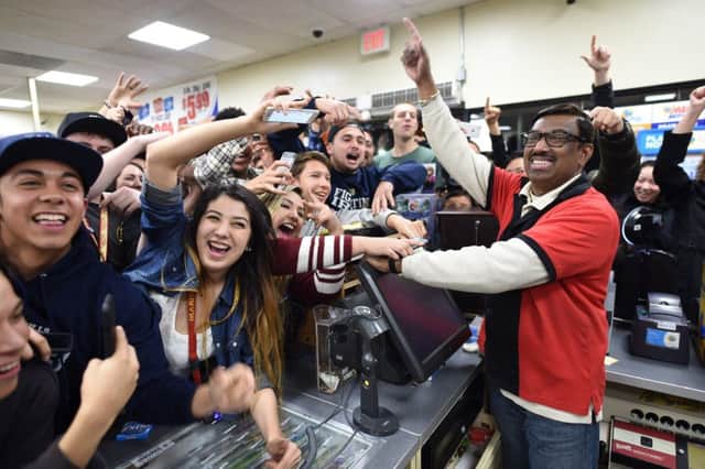 Cashier M Faroqui is mobbed in the Los Angeles store which sold one of the three winning tickets. Picture: AP