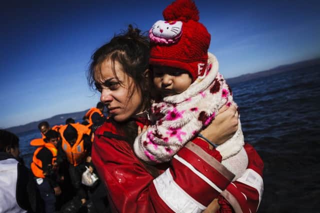 A Greek volunteer carries a baby girl in her arms after helping her out of an inflatable boat in the Mediterranean