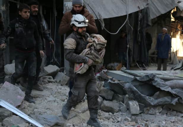 A Syrian Civil Defence worker carries a child wrapped in a blanket. Picture: AFP/Getty