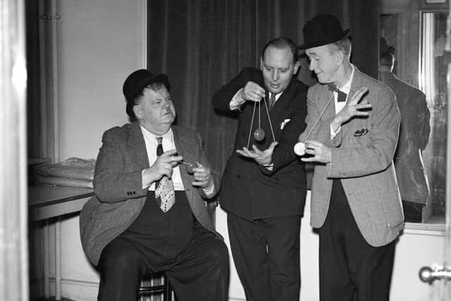 Stan Laurel and Oliver Hardy playing with yo-yos backstage at the Empire Theatre in Edinburgh in 1954