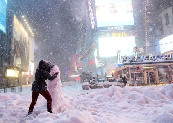 A woman decorates a snowman in Times Square as all cars but emergency vehicles are banned from New York's streets. Picture: Getty Images