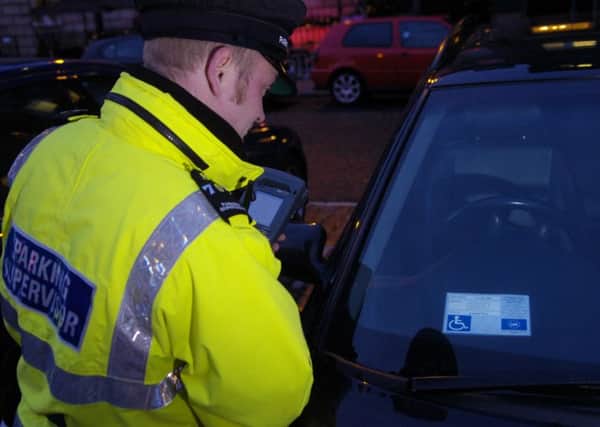 A Traffic Warden on patrol on George Street looking for fake disabled badges on parked cars.