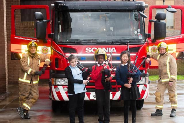 Firefighters, Paul Lavery, left and Steven Walls, look on as Kaylee Clugson, Damilola Fadun and Yin Chen play their pipes at Govan Fire Station. Picture: Wullie Marr/HPR