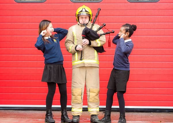 Firefighter, Steven Walls, tries his hand at the pipes as Yin Chen, and Savannah Batchelor from Riverside school, show their thoughts on his playing, at Govan Fire Station
Picture: Wullie Marr/HPR