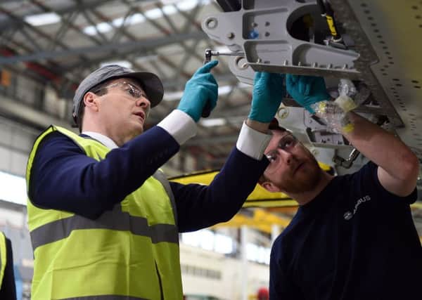 Chancellor George Osborne helps Airbus employee Sam Thurlow fix a part to a wing for an Airbus A400M during a visit to the Airbus factory in Filton, Bristol. Picture: Andrew Matthews/PA Wire