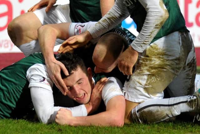 John McGinn is mobbed by his Hibernian team-mates after firing in the winner from 20 yards. Picture: Jane Barlow