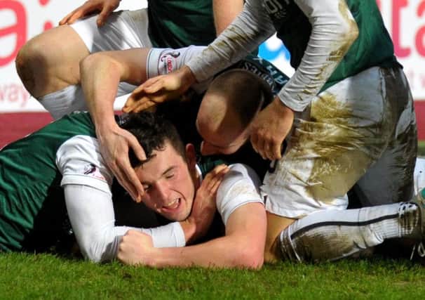 John McGinn is mobbed by his Hibernian team-mates after firing in the winner from 20 yards. Picture: Jane Barlow