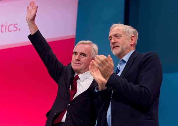 John McDonnell waves to delegates at Labours autumn conference as leader Jeremy Corbyn shows his approval. Picture: Getty Images