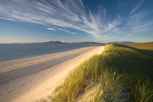 Strong summer sun lights the beach and dunes under dramatic streamers of cloud on Berneray in the Western Isles of Scotland. Picture: Alamy