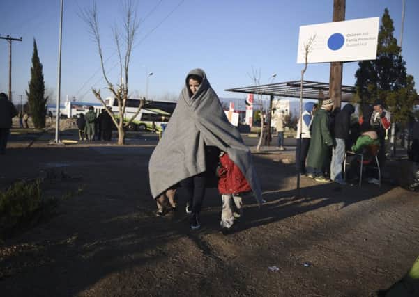 A migrant woman covered with a blanket walks with her children at a parking area near the northern Greek village of Idomeni. Picture: AP
