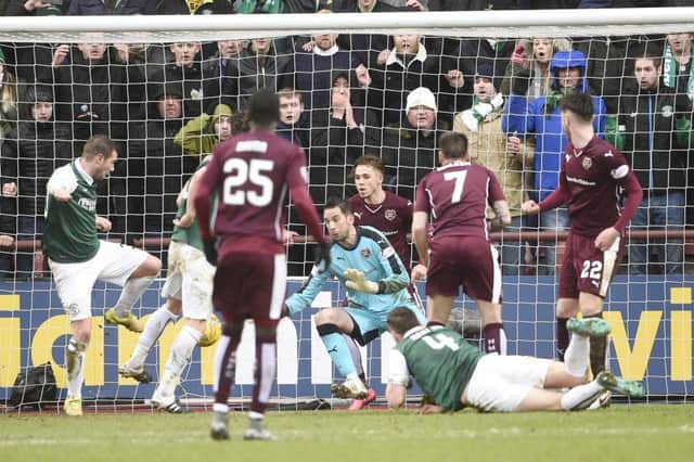Paul Hanlon shoots for goal as Hearts players watch on helplessly. Picture: Greg Macvean