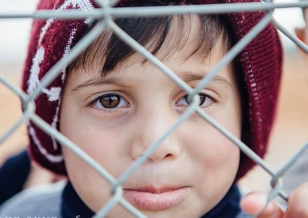 Young Syrian refugee behind camp fence