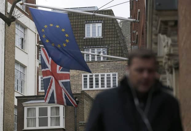 A man passes the EU flag hanging beside the Union flag at Europa House in London. Picture: AP