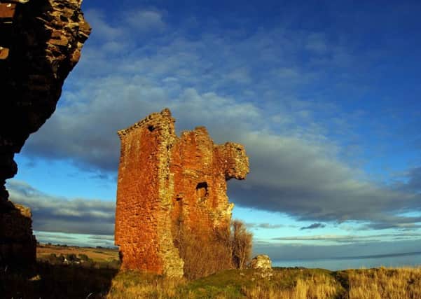 The remains of Red Castle perches high above the sea