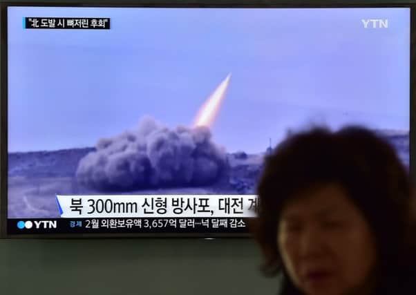 A woman walks past a public television screen showing file footage of a North Korean missile. Picture: AFP/Getty Images