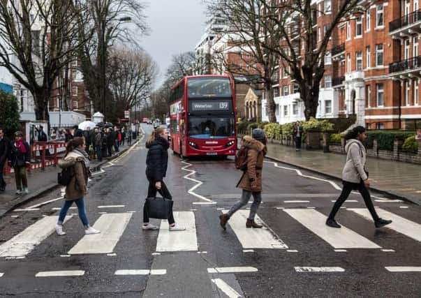 Beatles fans walk across the famous Abbey Road zebra crossing after paying tribute to producer George Martin. Picture: Getty