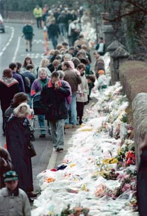People looking at floral tributes lining the road by Dunblane Primary School three days after the shooting in 1996. Picture: PA