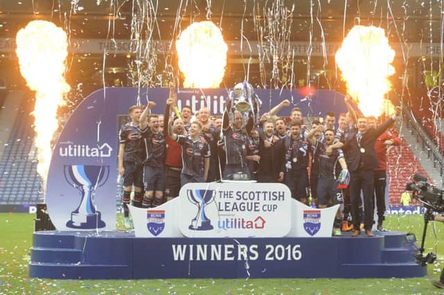 Andrew Davies, centre, holds the trophy aloft after Ross County defeated Hibernian in the Leagu Cup final. Picture: Greg Macvean