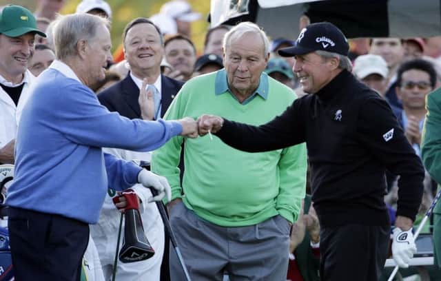 Arnold Palmer, centre, watches as Jack Nicklaus, left, and Gary Player touch fists after Palmer hit his ceremonial drive on the first tee before the 2014 Masters. Palmer will not be hitting the tee shot this year. Picture: David J Phillip/AP