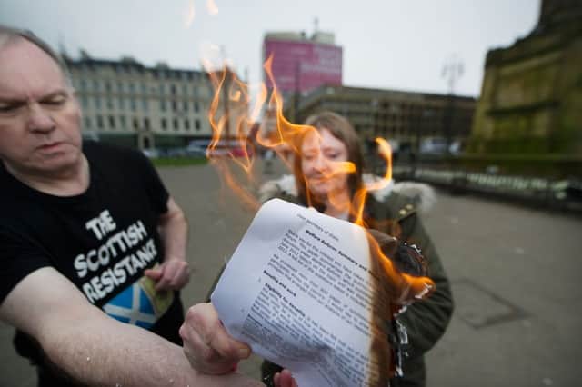 Sean Clerkin burns a copy of a Tory welfare reform paper in Glasgow's George Square. Picture: John Devlin/TSPL