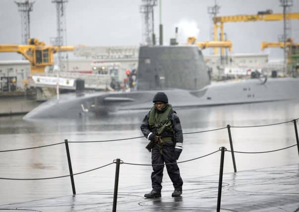 A member of the armed services walks on the deck of Vanguard-class submarine HMS Vigilant, one of the UK's four nuclear warhead-carrying submarines, with Astute-class submarine HMS Artful behind at HM Naval Base Clyde. Picture: Danny Lawson/PA Wire