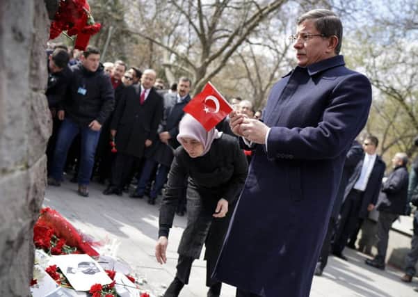 Turkey's Prime Minister Ahmet Davutoglu holds a national flag as he and his wife Sare Davutoglu, left, lay carnations at the explosion site in Ankara, Turkey Picture: AP Photo/Umit Bektas, Pool