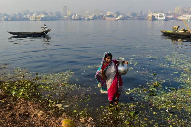 A woman collects contaminated water to be used on produce at a vegetable market from the Buriganga river in the Bangladeshi capital Dhaka. Left a womans hands show the effects of the water. Picture: Getty Images