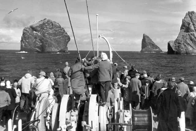 Tourists in the 1970s outnumber gannets in a view from the foredeck of a cruise ship.
