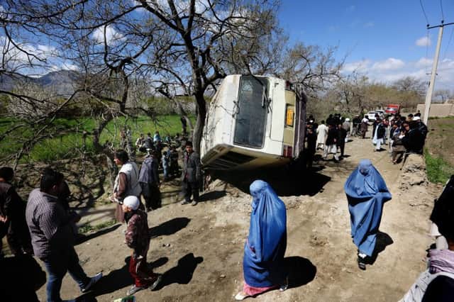 Afghan women walk past a damaged bus after a roadside bomb on the outskirts of Kabul, Afghanistan. Picture: AP