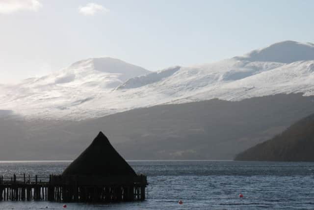 Scottish Crannog Centre on Loch Tay with a snow capped Ben Lawers behind.