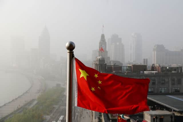 A Chinese national flag flutters against the office buildings at the Shanghai Bund shrouded by pollution and fog in Shanghai, China. Picture: AP