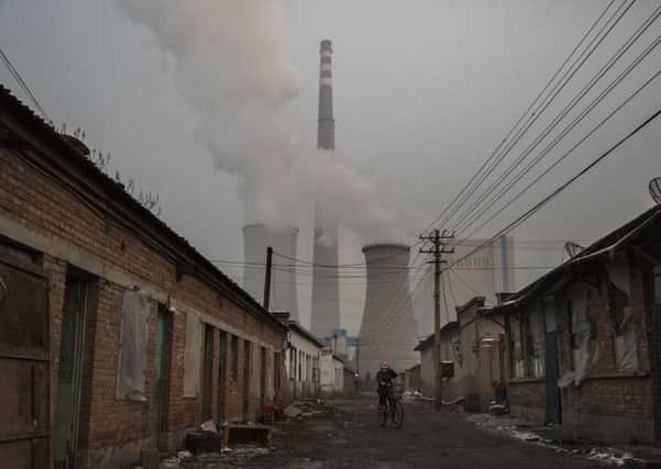 A Chinese woman rides her bike near a coal fired power plant on the outskirts of Beijing. Last year was the hottest on record globally, measuring 0.9C above the 20th-century average. Picture: Kevin Frayer/Getty Images