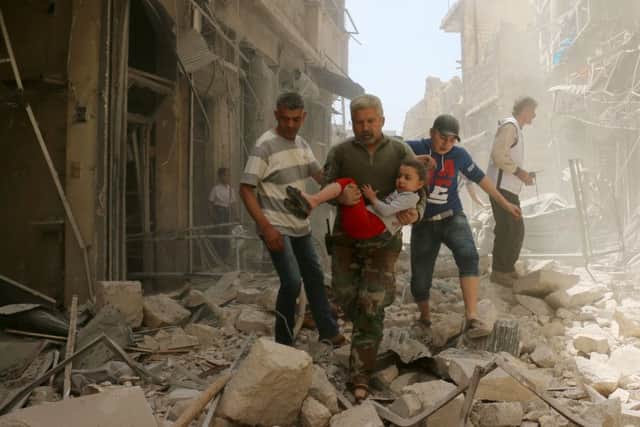 A Syrian man carries a child as they evacuate an area following a reported airstrike on April 22. Picture: AFP/Getty Images