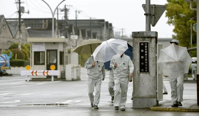 Workers under umbrellas leave the gate of Mitsubishi Motors Co's main factory Mizushima Plant in Kurashiki. Picture: AP