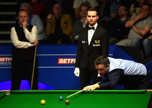 Alan McManus plays a shot as fellow Scot John Higgins watches on at the Crucible yesterday. Picture: Getty