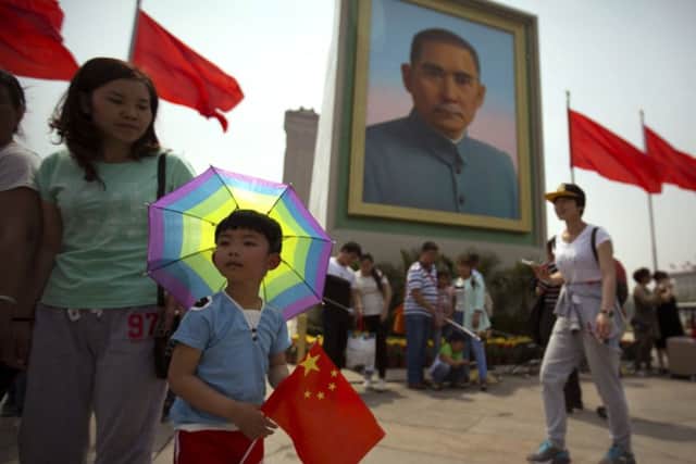 A boy holds a Chinese flag as he stands in front of a portrait of Sun Yat-sen at Tiananmen Square on the eve of the May Day holiday in Beijing. China is now Scotlands top export location in Asia. Picture: AP Photo/Mark Schiefelbein