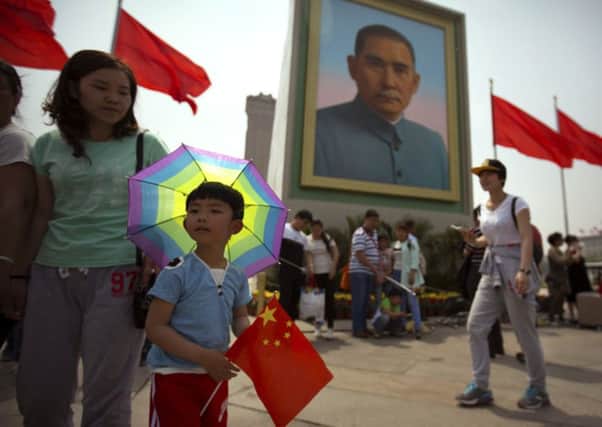 A boy holds a Chinese flag as he stands in front of a portrait of Sun Yat-sen at Tiananmen Square on the eve of the May Day holiday in Beijing. China is now Scotlands top export location in Asia. Picture: AP Photo/Mark Schiefelbein