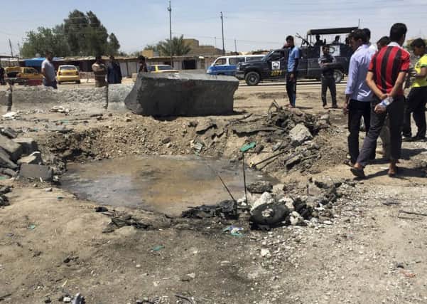 Civilians inspect a crater caused by a car bombing at an open-air market selling fruit, vegetables and meat in Baghdad's southeast suburb of Nahrawan, Iraq, Saturday Picture: AP Photo/Ali Abdul Hassan