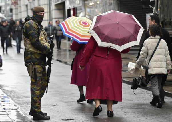 Women with umbrellas walk past a soldier patrolling the Rue Neuve in Brussels. Picture: AFP/Getty Images