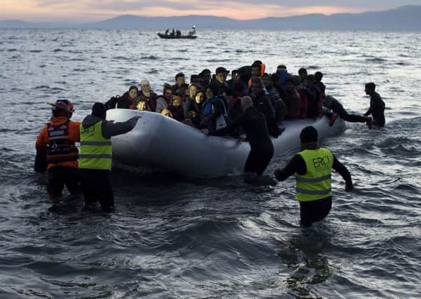 Volunteers and Lifeguards help an inflatable boat with refugees, crossing the sea from Turkey. Picture: Alexander Koerner/Getty Images