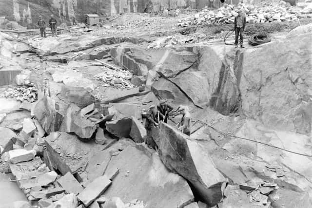 Three quarrymen working at splitting a large block at Kemnay Quarries in Aberdeenshire. One is wielding a pneumatic drill while the other two are using large crowbars. PIC National Geological Survey/NERC