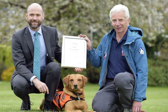 PDSA vet John Faulkner with Rauour, his handler John Romanes and his PDSA commendation.