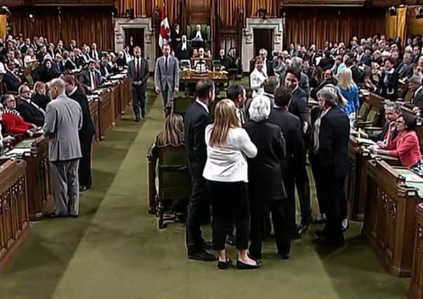 Trudeau wading into a clutch of lawmakers, mostly opposition members, and pulling a lawmaker through the crowd. Picture: AP